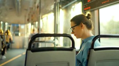 Toplu taşıma. Tramvaydaki gözlüklü kadın akıllı telefon konuşmaları ve arkadaşlarıyla mesajlaşmalar yapıyor. Şehir, şehir, ulaşım.