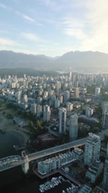 Dikey video. Vancouver şehir merkezindeki gökdelenlerin, Stanley Park 'ın, False Creek' in ve dağların hava manzarası, Britanya Kolumbiyası, Kanada şafak vakti.