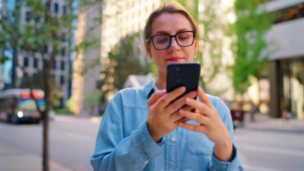 Běloška Brýlích Stojí Uprostřed Města Používá Smartphone Mrakodrapy Auta Jsou — Stock video