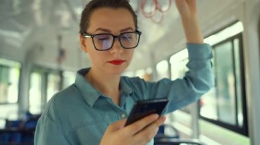 Toplu taşıma. Tramvaydaki gözlüklü kadın akıllı telefon konuşmaları yapıyor ve arkadaşlarıyla mesajlaşıyor. Şehir, şehir, ulaşım. Yavaş çekim