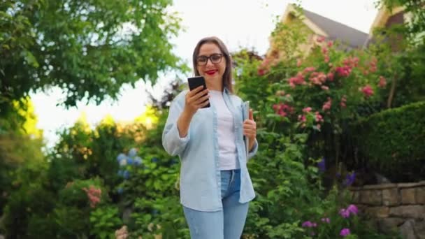 Mujer Feliz Con Portátil Teléfono Inteligente Sus Manos Pie Floreciente — Vídeos de Stock