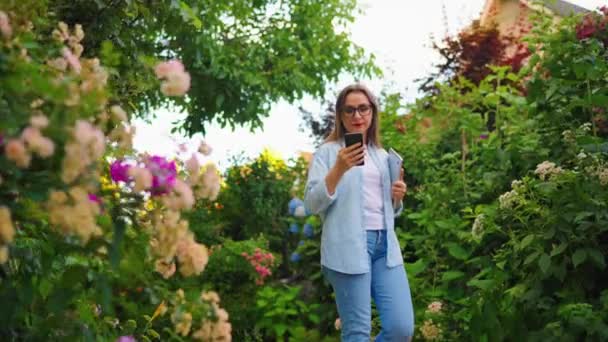 Mujer Feliz Con Laptop Smartphone Sus Manos Caminando Por Floreciente — Vídeos de Stock