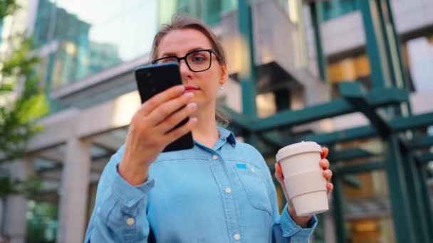 Mujer Caucásica Gafas Pie Calle Uso Teléfonos Inteligentes Beber Café — Vídeo de stock