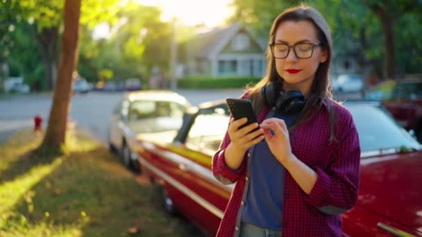 Woman Headphones Standing Outdoors Red Vintage Car Using Smartphone Blooming — Stock Video