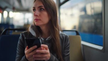 Toplu taşıma. Tramvayda akıllı telefon kullanan, arkadaşlarıyla mesajlaşan bir kadın, ağır çekim. Şehir, şehir, ulaşım.