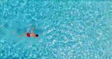Kırmızı şortlu bir adam havuzda yüzüyor. Yaz yaşam tarzı. Yavaş çekim