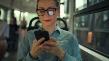 Toplu taşıma. Tramvaydaki gözlüklü kadın akıllı telefon konuşmaları yapıyor ve arkadaşlarıyla mesajlaşıyor. Şehir, şehir, ulaşım.