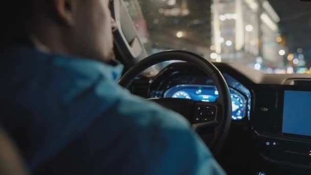 男人开车穿过夜城的街道 车窗上闪烁着光芒 从车子的后座上看 — 图库视频影像