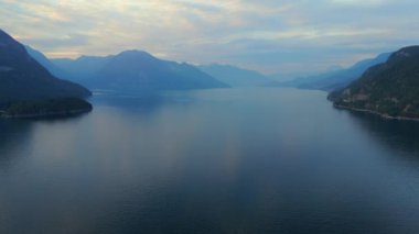 Akşamları Vancouver 'ın kuzeyindeki deniz manzarası. Gün batımı bulutlu gökyüzü ve dağların siluetleri. British Columbia, Kanada.