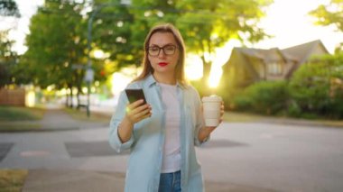 Elinde akıllı telefon olan mutlu bir kadın yaz akşamları mahallede dolanıyor. Yavaş çekim