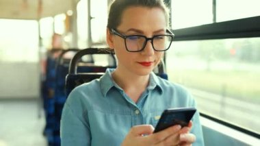 Toplu taşıma. Tramvaydaki gözlüklü kadın akıllı telefon konuşmaları yapıyor ve arkadaşlarıyla mesajlaşıyor. Şehir, şehir, ulaşım.