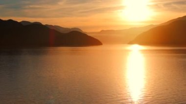 Vancouver 'ın kuzeyindeki güzel günbatımında deniz manzarası. Dağların siluetlerinin üzerine güneş batıyor. British Columbia, Kanada.