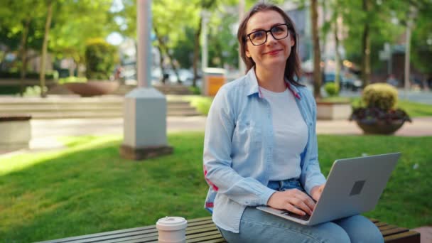 在公园里工作一天后拿着笔记本电脑和咖啡坐在公园里的女人的画像 慢动作 — 图库视频影像