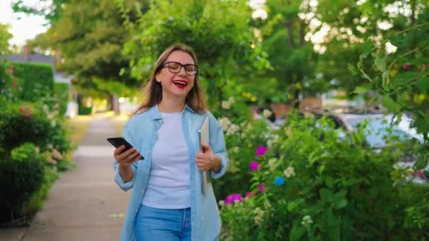 Ευτυχισμένη Γυναίκα Φορητό Υπολογιστή Και Smartphone Στα Χέρια Της Περπατώντας — Αρχείο Βίντεο