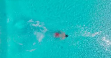 Top down view as a man dives into the pool and swims. Slow motion