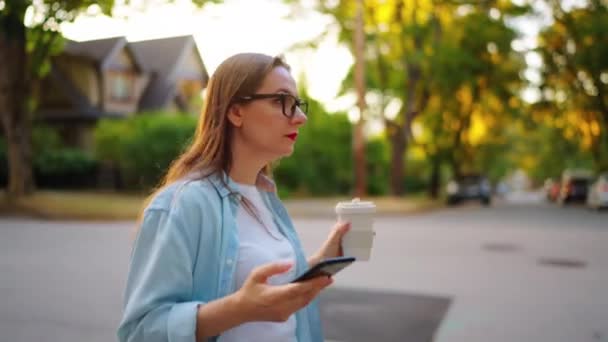 Ευτυχισμένη Γυναίκα Smartphone Στο Χέρι Της Περπατώντας Στη Γειτονιά Βράδυ — Αρχείο Βίντεο