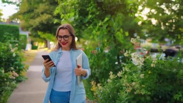 Šťastná Žena Notebookem Smartphonem Rukou Procházející Kvetoucí Zahradou Nebo Zelenou — Stock video