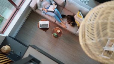 Kadının notlar yazıp konferans dinlemesi, evdeki kanepede uzanması. Yanında oturan tüylü kediler.