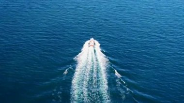 Derin mavi bir denizde, beyaz dalgalı hızlı teknenin havadan görünüşü. Drone 'dan deniz burnu. Seyahat videosu
