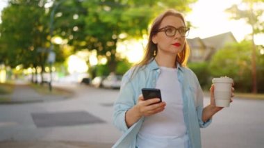 Elinde akıllı telefon olan mutlu bir kadın yaz akşamları mahallede dolanıyor. Yavaş çekim