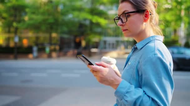 Běloška Brýlích Chodí Městě Používá Smartphone Pije Kávu Mrakodrapy Jsou — Stock video