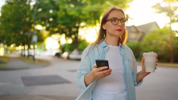 Ευτυχισμένη Γυναίκα Smartphone Στο Χέρι Της Περπατά Στη Γειτονιά Βράδυ — Αρχείο Βίντεο