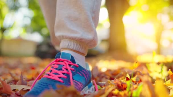女人在慢跑或日落时走路时系鞋带 秋天的黄叶 慢动作 — 图库视频影像