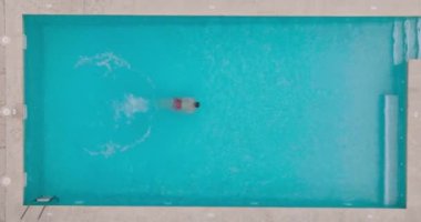 Top down view as a man dives into the pool and swims. Slow motion