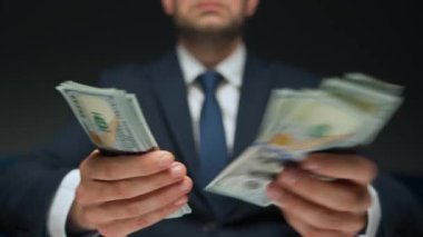 Resmi olarak giyinmiş bir adam Amerikan dolarlarını sayıyor, yakın plan. Yatırım, başarı, finansal beklentiler veya kariyer ilerlemesi kavramı.