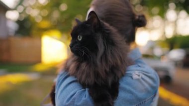 Siyah kedisini kucağına alıp kucaklayan güzel bir kadın. Kedi merakla etrafına bakıyor.