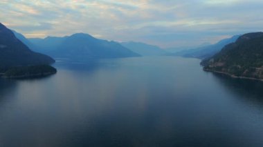 Akşamları Vancouver 'ın kuzeyindeki deniz manzarası. Mavi bulutlu gökyüzü ve dağların siluetleri. British Columbia, Kanada.