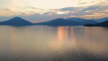 Akşamları Vancouver 'ın kuzeyindeki deniz manzarası. Gün batımı bulutlu gökyüzü ve dağların siluetleri. British Columbia, Kanada.