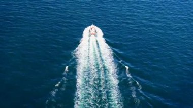 Derin mavi bir denizde beyaz dalgalı hızlı bir teknenin havadan görüntüsü. Drone 'dan deniz burnu. Seyahat videosu