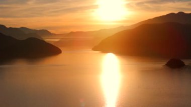 Vancouver 'ın kuzeyindeki güzel günbatımında deniz manzarası. Dağların siluetlerinin üzerine güneş batıyor. British Columbia, Kanada.