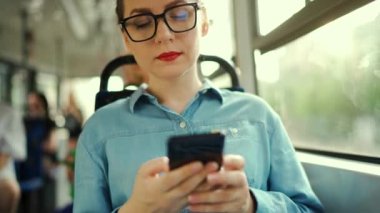 Toplu taşıma. Tramvaydaki gözlüklü kadın akıllı telefon konuşmaları yapıyor ve arkadaşlarıyla mesajlaşıyor. Şehir, şehir, ulaşım.