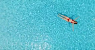 Kırmızı mayo giymiş bir kadının havuzda sırt üstü yatışı. Rahatlatıcı konsept, yaz yaşam tarzı