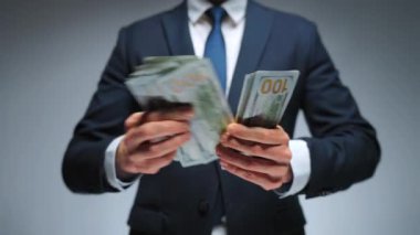 Resmi olarak giyinmiş bir adam Amerikan dolarlarını sayıyor, yakın plan. Yatırım, başarı, finansal beklentiler veya kariyer ilerlemesi kavramı.