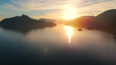 Vancouver 'ın kuzeyindeki güzel günbatımında deniz manzarası. Dağların siluetlerinin üzerine güneş batıyor. British Columbia, Kanada.