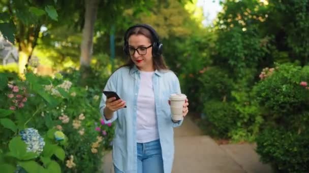 Mujer Feliz Gafas Auriculares Con Café Teléfono Inteligente Sus Manos — Vídeos de Stock