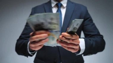 Resmi olarak giyinmiş bir adam Amerikan dolarlarını sayıyor, yakın plan. Yatırım, başarı, finansal beklentiler veya kariyer ilerlemesi kavramı.