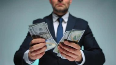 Resmi olarak giyinmiş bir adam Amerikan dolarlarını sayıyor, yakın plan. Yatırım, başarı, finansal beklentiler veya kariyer ilerlemesi kavramı.