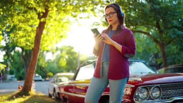 Kulaklıklı Bir Kadın Kırmızı Arabanın Yanında Duruyor Yaz Günü Yeşil — Stok video