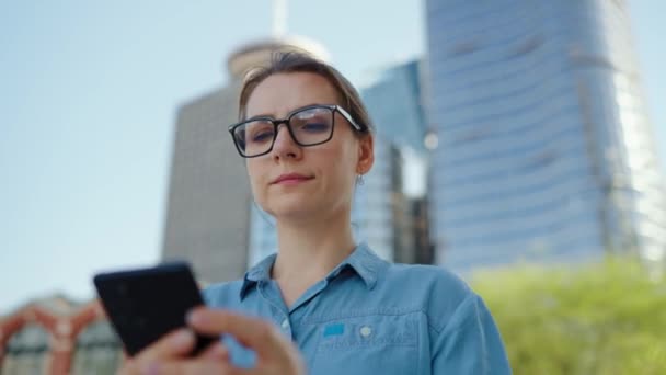 Mujer Caucásica Gafas Caminando Por Ciudad Usando Smartphone Los Rascacielos — Vídeo de stock