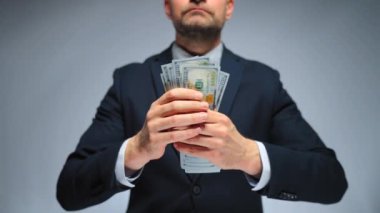 Resmi olarak giyinmiş bir adam Amerikan dolarlarını sayıyor, yakın plan. Yatırım, başarı, finansal beklentiler veya kariyer ilerlemesi kavramı.