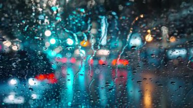 Akşam şehrinin çok renkli ışıkları ve yağmurlu bir pencereden geçen arabalar. Yağmurlu depresif hava