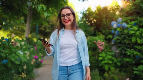 Ευτυχισμένη Χαμογελαστή Γυναίκα Smartphone Στο Χέρι Της Περπατώντας Μέσα Από — Αρχείο Βίντεο