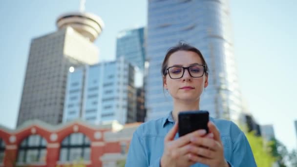 Λευκή Γυναίκα Γυαλιά Που Περπατάει Στην Πόλη Και Χρησιμοποιεί Smartphone — Αρχείο Βίντεο