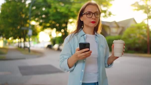 Ευτυχισμένη Γυναίκα Smartphone Και Τον Καφέ Στα Χέρια Της Περπατώντας — Αρχείο Βίντεο