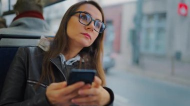 Toplu taşıma. Tramvayda akıllı telefon kullanan, arkadaşlarıyla mesajlaşan bir kadın. Şehir, şehir, ulaşım.