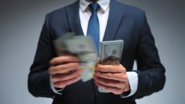 Resmi olarak giyinmiş bir adam Amerikan dolarlarını sayıyor, yakın plan. Yatırım, başarı, finansal beklentiler veya kariyer ilerlemesi kavramı.